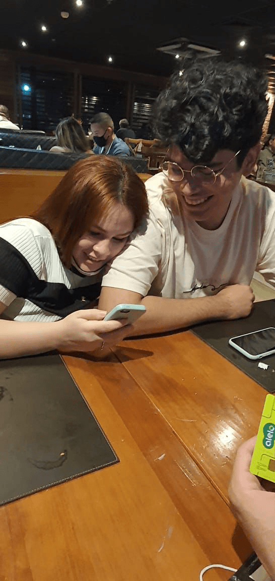 Adriana e Matheus sorrindo juntos em um restaurante